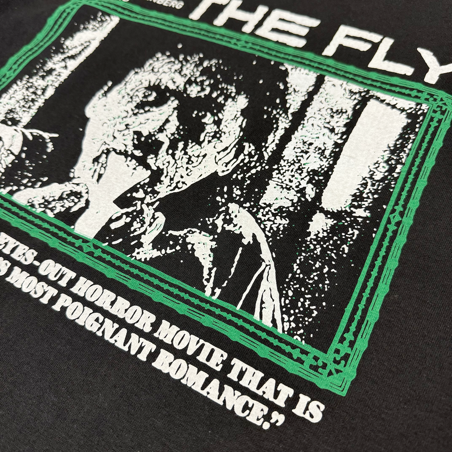 Detailed and zoomed in photo of the front of the shirt, which features the main character vomiting fluid with a green border.