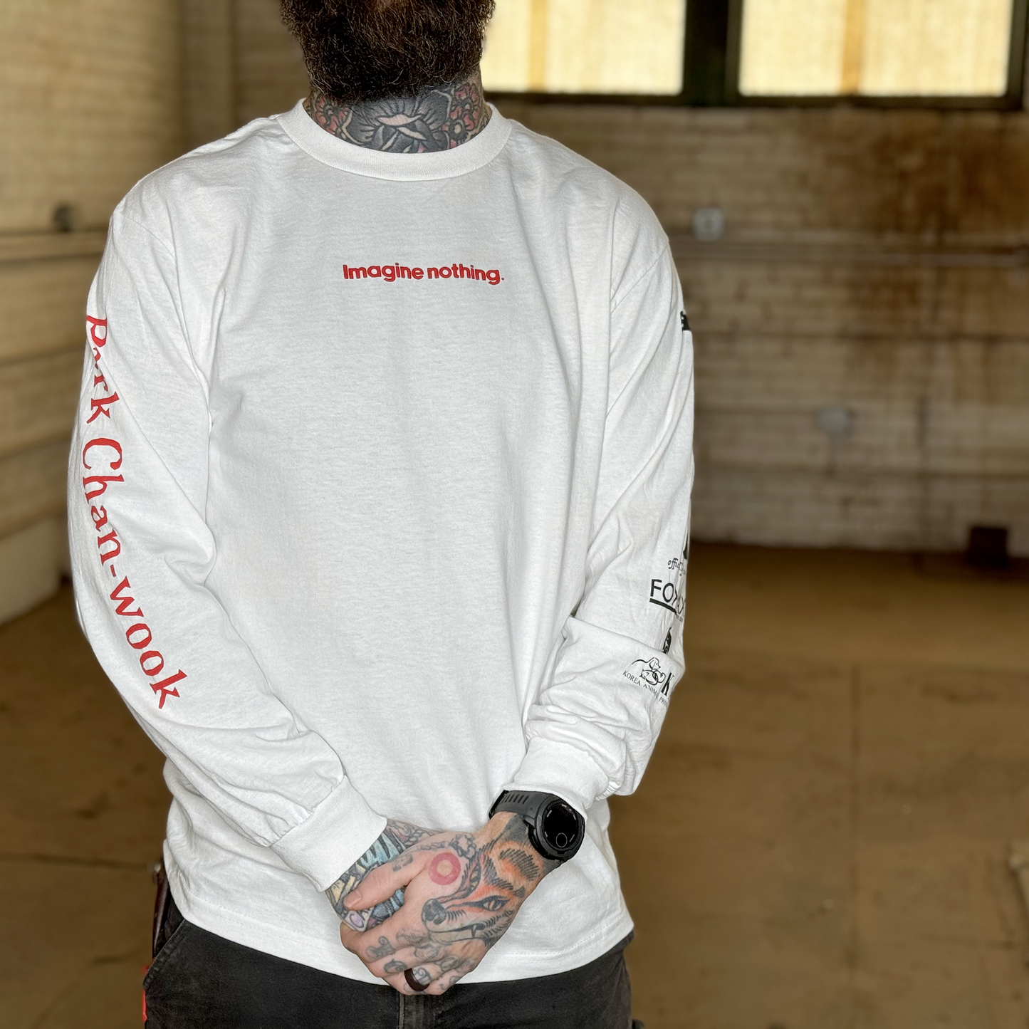 A model wearing of the shirts that reads "Imagine nothing." on the front. The sleeve print is slightly visible because of the models crossed hands.