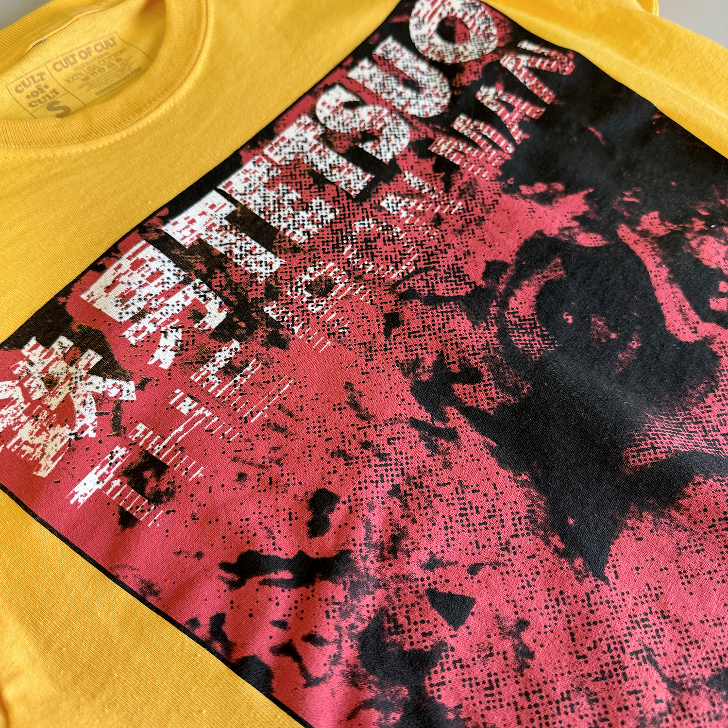 Zoomed in detail of the front of the yellow shirt. The main character is distorted on the front of the shirt, printed in red and black. The front also reads "Tetsuo The Iron Man" in white.