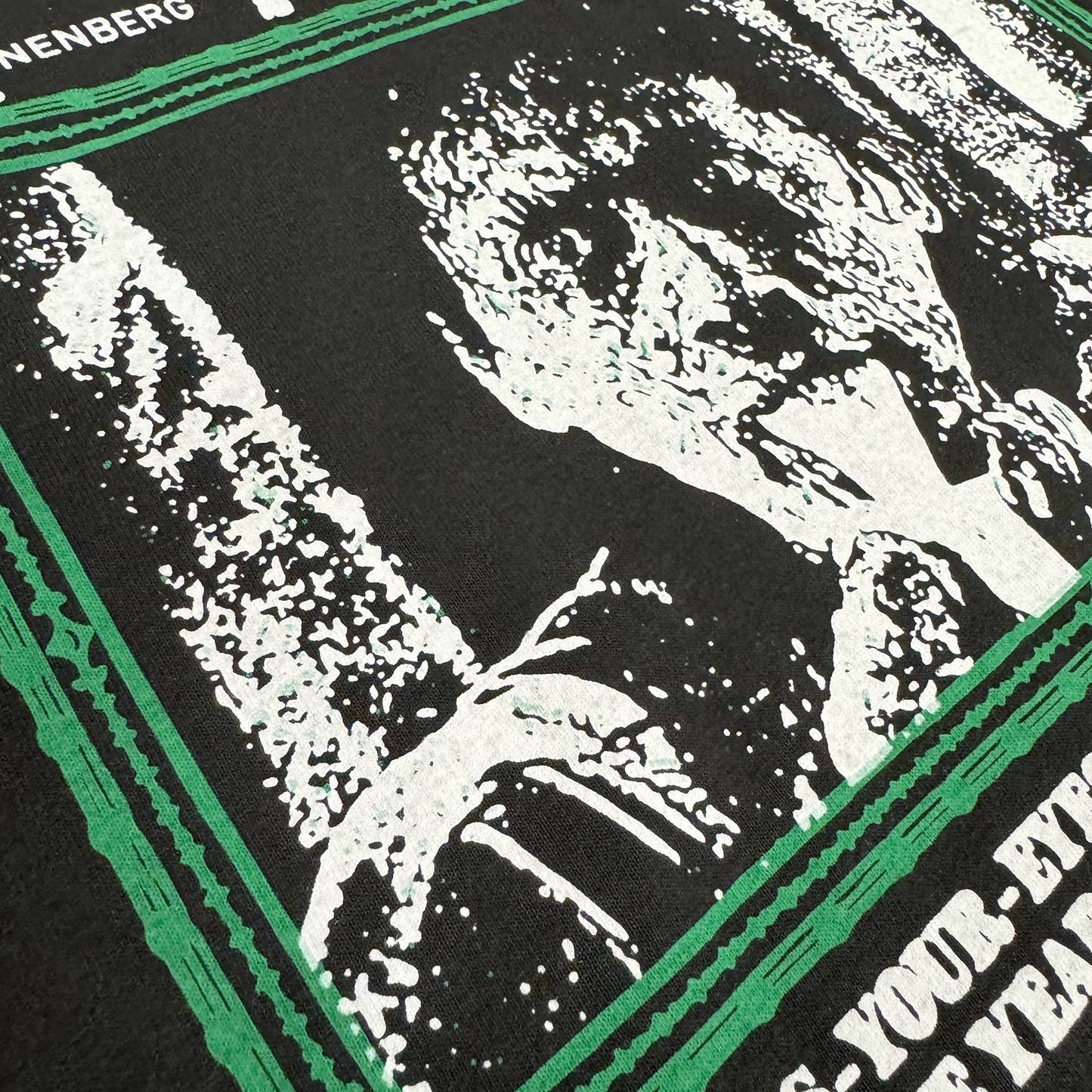Detailed and zoomed in photo of the front of the shirt, which features the main character vomiting fluid with a green border.