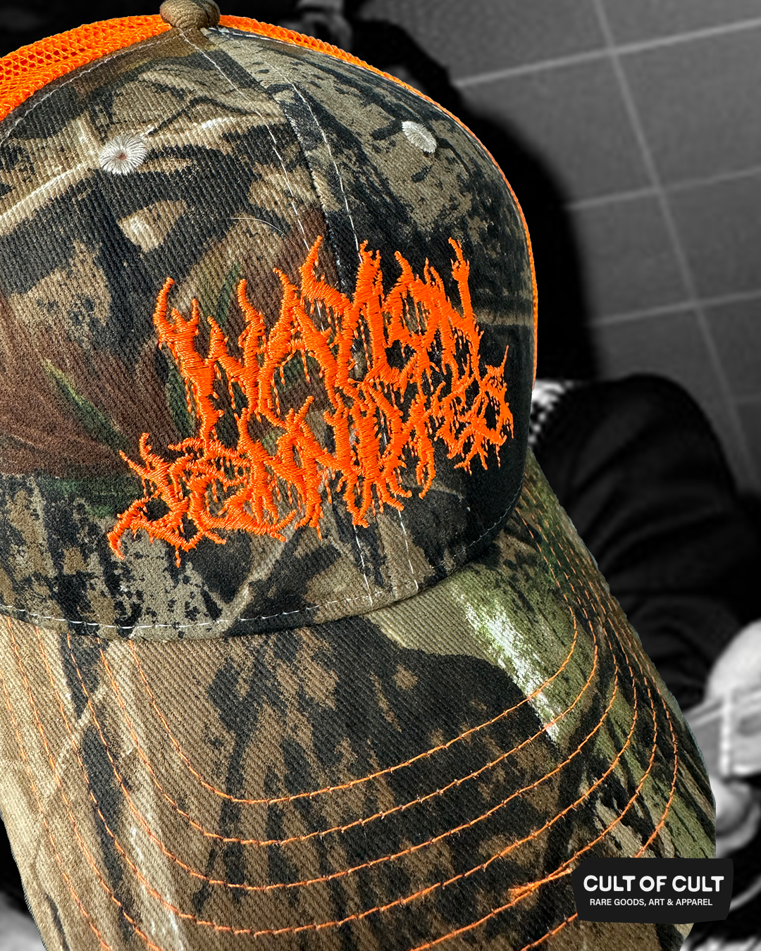 a close up view of the orange and camo Waylon Jennings trucker hat